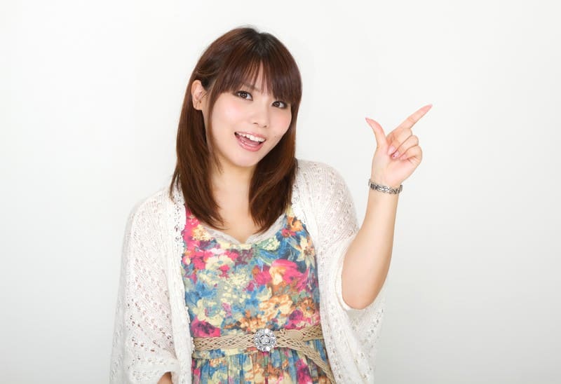 白い背景の前で笑顔で横を指差して「こちらをどうぞ」と案内する画像