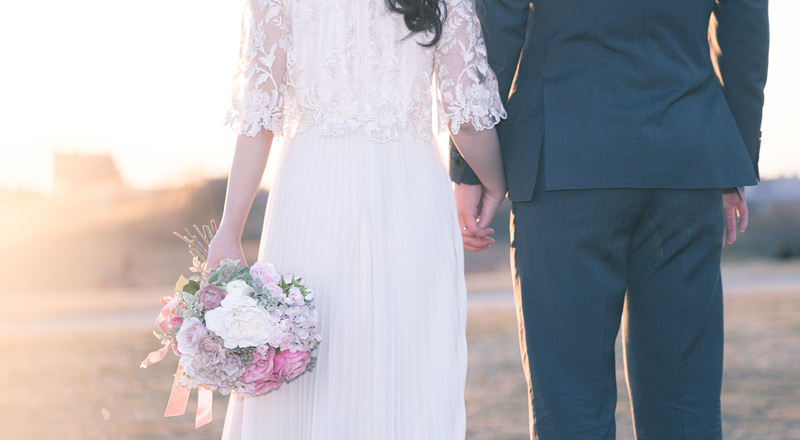 未来へ向かって手を握り歩き出す新婚夫婦のウェディング画像