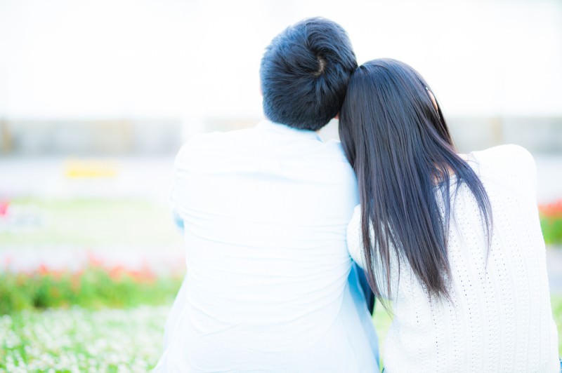 屋外で肩を寄せる男女の後ろ姿の画像