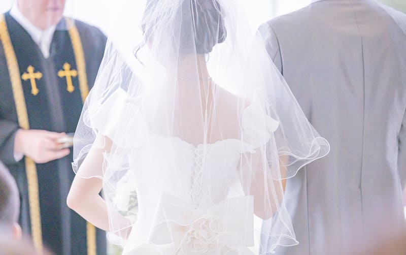 牧師の前で誓いの言葉を述べる花嫁、新郎と教会式の結婚式の写真