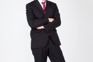 真剣な表情で腕を組むスーツ姿の男性画像