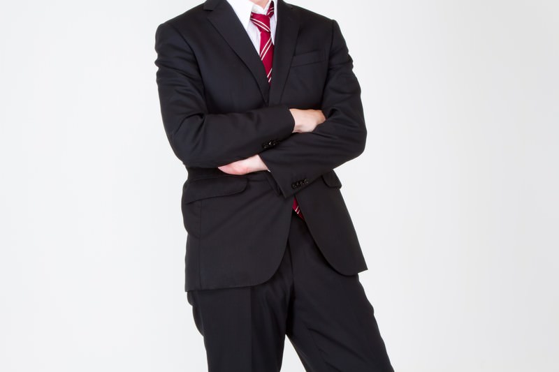真剣な表情で腕を組むスーツ姿の男性画像